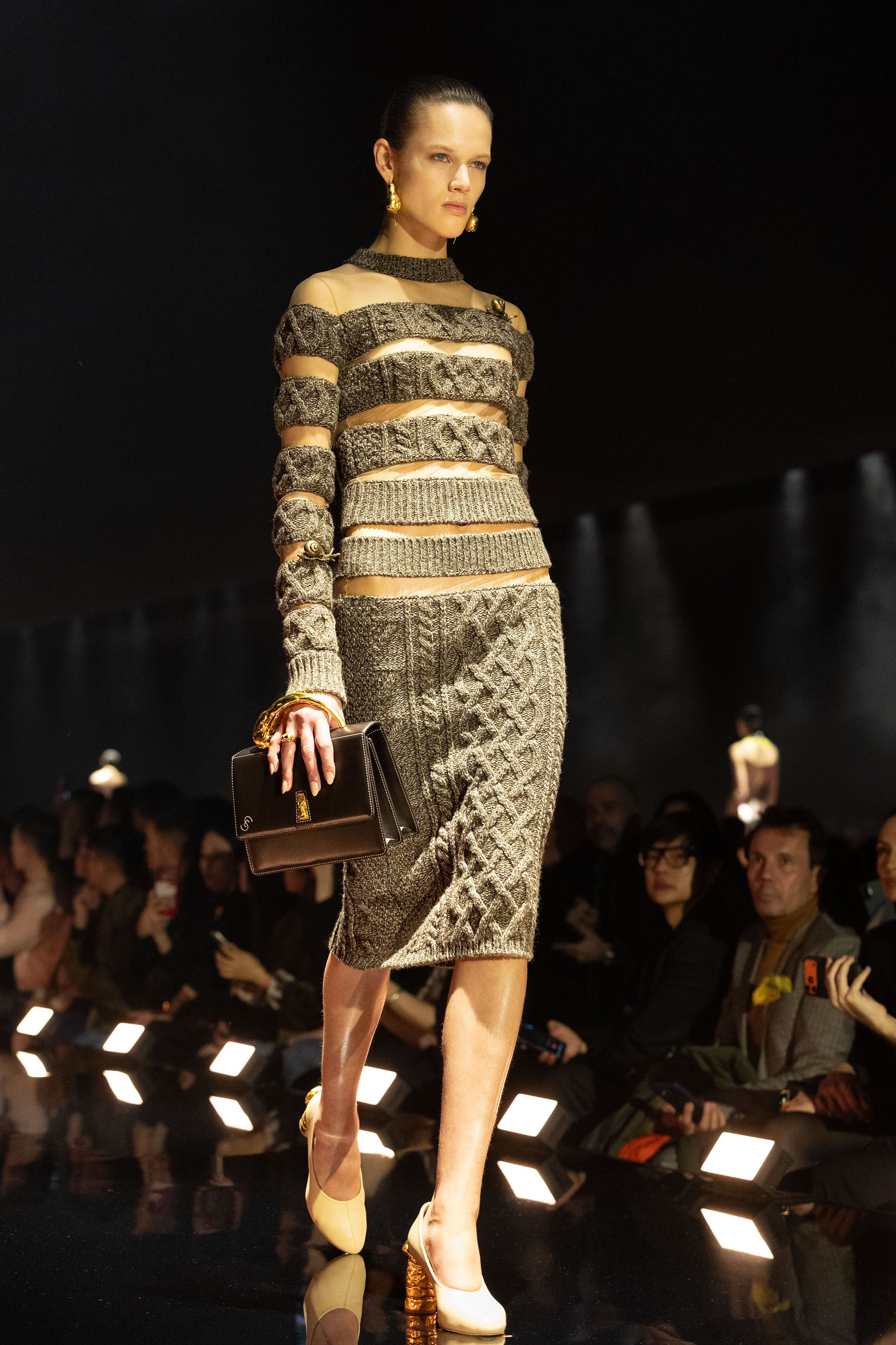 Schiaparelli 2026秋冬系列延续品牌标志性的超现实主义美学，在金色灯光的T台上呈现极具雕塑感的廓形。沙金色与黑金色成为主调，褶皱礼服、雕塑式西装与高腰裙装强化身体线条。经典的金属装饰、夸张肩线以及精致刺绣细节构成强烈视觉符号，使整场秀既华丽又充满戏剧张力。设计师通过结构与面料的张力对比，让高级定制的艺术精神融入现代女性衣橱-顽石频道趋势研究